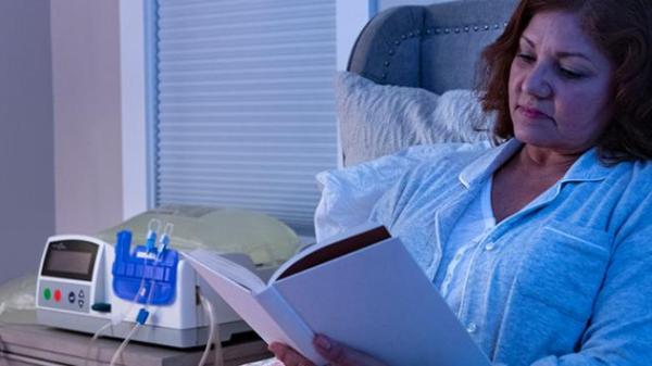 A women reads in bed next to her APD system